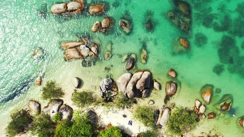 Paradise shore of tropical island with old limestone cliffs naturally caved by saltwater of calm tur