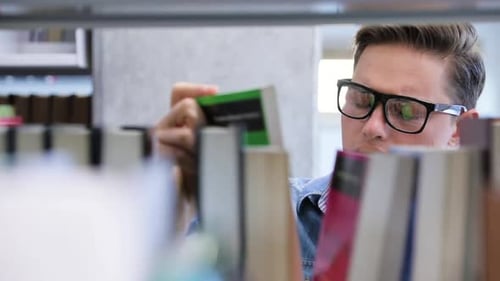 College Library. Male Student Searching For Book On Bookshelves