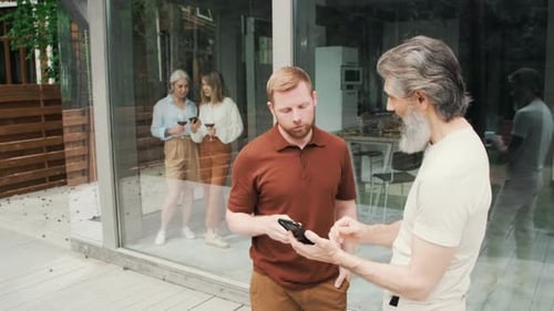 Men Looking at Cell Phone and Talking