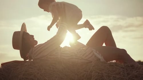 Young mother hugs her baby on the background of sunset in the field