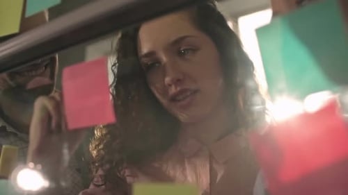 Team Brainstorming on Glass Wall with Sticky Notes