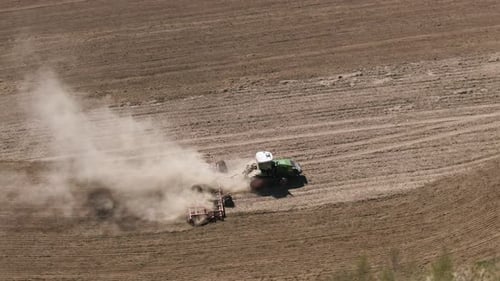Aerial Top View of Tractor Cutting Furrows in Farm Field for Sowing Farm Tractor with Rotary Harrow