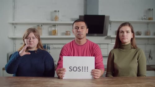 Adults Holding Signs at Kitchen Table Indoors