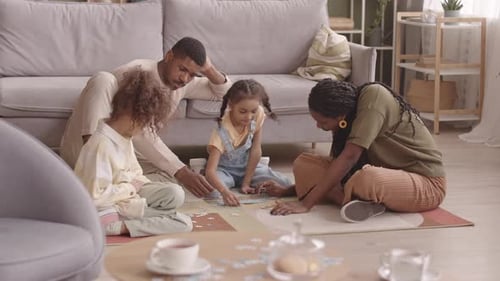 African American Family Solving Puzzles on Floor in Living Room