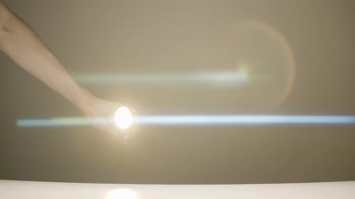 Glowing Lightbulb Rolling Across a White Surface