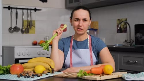 Femme agacée mangeant une branche de céleri dans la cuisine