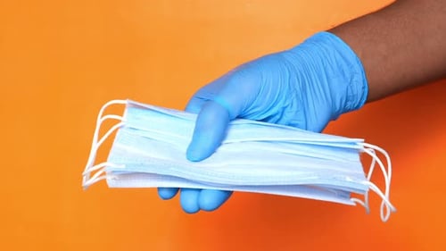Doctor Hand in Medical Glove Holding Protective Surgical Face Mask, Close Up