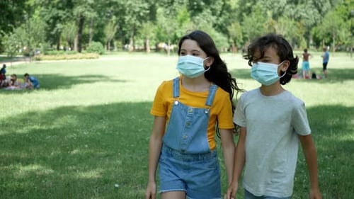 A cute boy and girl met in a summer park, put on masks and went for a walk