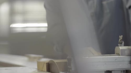 Man Cutting Wood with Saw in Shop