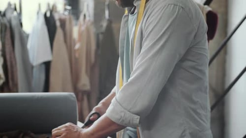 Male Tailor Cutting Fabric in Dressmaking Studio