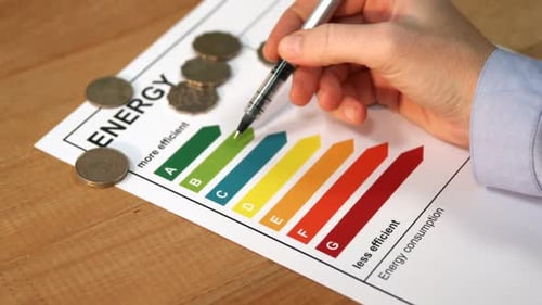 Marking Energy Efficiency Chart with Pen on Desk
