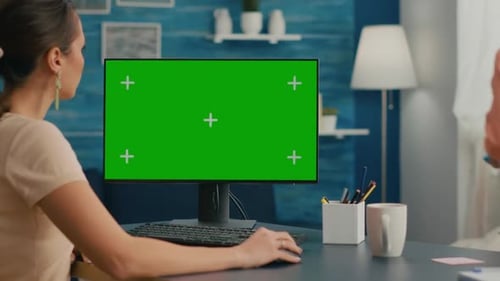 Woman Looking at Computer with Green Screen Mock Up Chroma Key Display