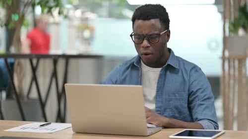 Young Adult Frustrated at Laptop in Modern Workplace