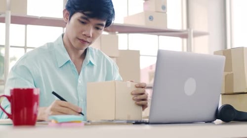 Adult Works on Laptop With Boxes at Desk