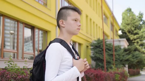A Caucasian Teenage Boy Looks Around As He Waits for Something Side View a School