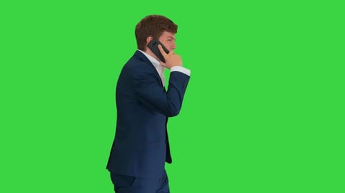 Handsome Young Businessman Talking on the Phone While Walking on a Green Screen, Chroma Key.