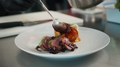The chef pours sauce over the filet mignon. Serving food in a restaurant.