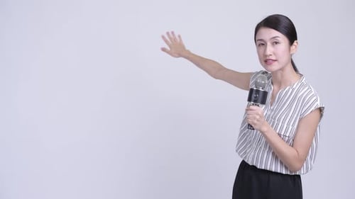 Glückliche, schöne asiatische Geschäftsfrau als Nachrichtensprecherin, die etwas präsentiert
