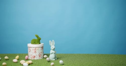 Kaninchenspielzeug auf blauem Hintergrund aus grünem Gras mit vielen farbigen Eiern