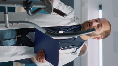 Vertical Video Doctor Giving Assistance to Old Woman Exercising on Stationary Bike
