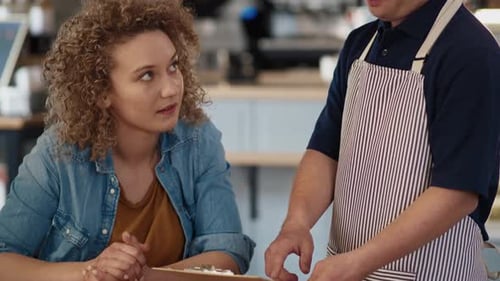 Caucasian waiter with down syndrome showing and discussing menu to the client at the cafe. Shot with