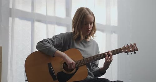 Teenager Playing Acoustic Guitar Indoors During Daytime
