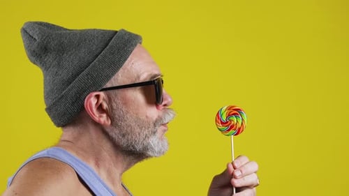 Bearded senior man eating candy