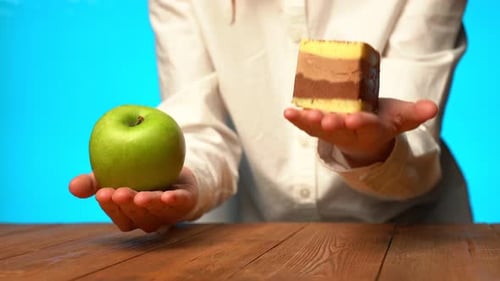 Mujer joven sobre un fondo azul elige entre un pastel pegajoso o una manzana verde