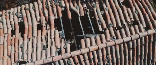 Homem de pé em uma casa abandonada com um buraco no telhado