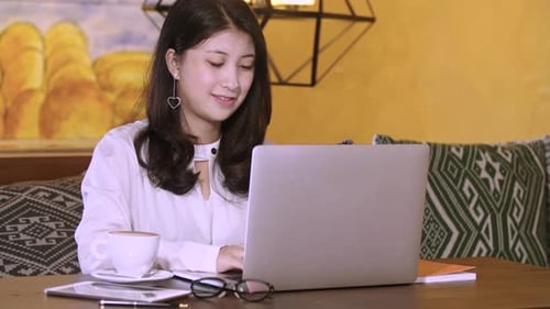 Young Woman Works on Laptop in Cafe