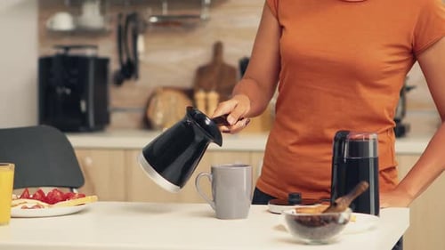 Woman Pours Fresh Coffee in Bright Kitchen