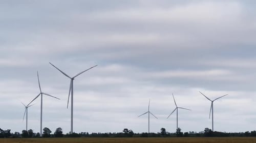 Wind Turbines Rotating on Cloudy Day in a Rural Field