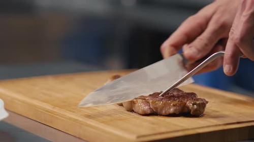 Chef Cutting Steak on Wooden Cutting Board