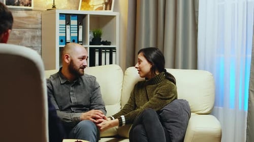 Traurige Freundin hält Ehemann Hände auf Couch sitzend