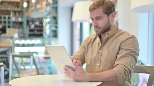 Attractive Young Man with Digital Tablet in Cafe