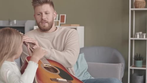 Adult Man Teaches Child How To Play Guitar