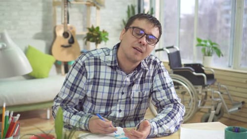 Man Drawing at Desk in Bright Home Setting