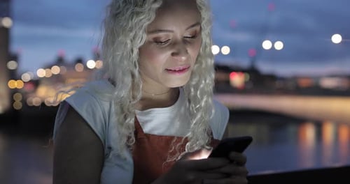 Pretty young woman typing message on smartphone, London, UK