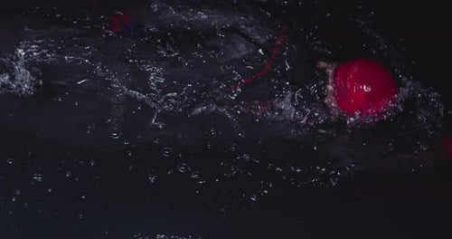 Triathlon Athlete Swimming in Dark Night Wearing Wetsuit