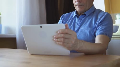 Adult Man Uses a Tablet at Home