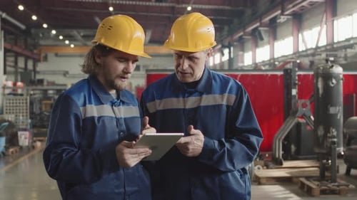Male Plant Workers With Tablet Having Conversation At Workplace