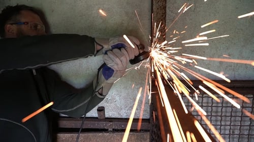Un trabajador que usa una amoladora corta metal en un taller
