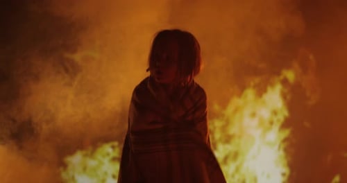 Figure Stands Before Raging Fire at Night