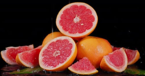 Juicy Grapefruits with Water Droplets on Black Background