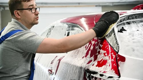 Worker Cleaning a Modern Car at Car Wash