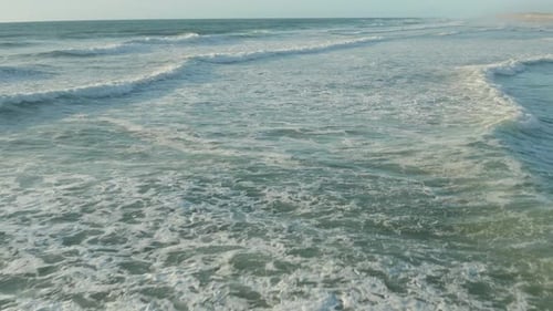 Waves Crashing Along a Sandy Beach from Above