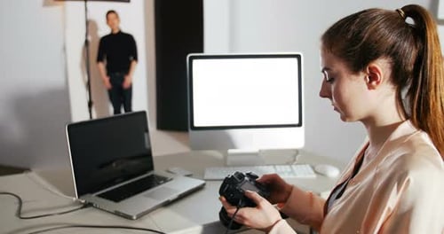 Female photographer reviewing captured photos in his digital camera at studio