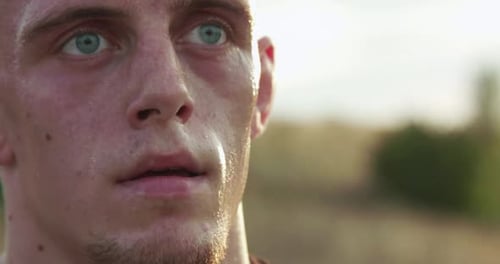 Close Portrait of Strong Thoughtful Kickboxer Looking at Sky at Camera Outdoors