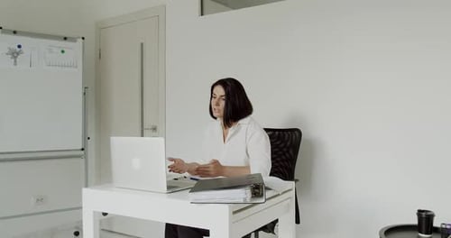 Female Teacher Conducts an Online Lecture on a Laptop in the Office