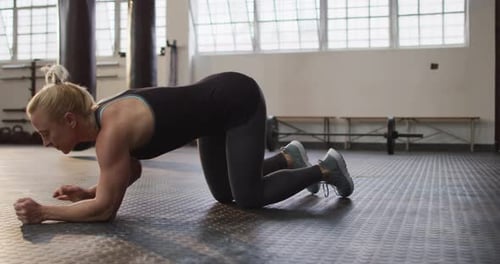 Side view of fit caucasian woman performing plank exercise at the gym